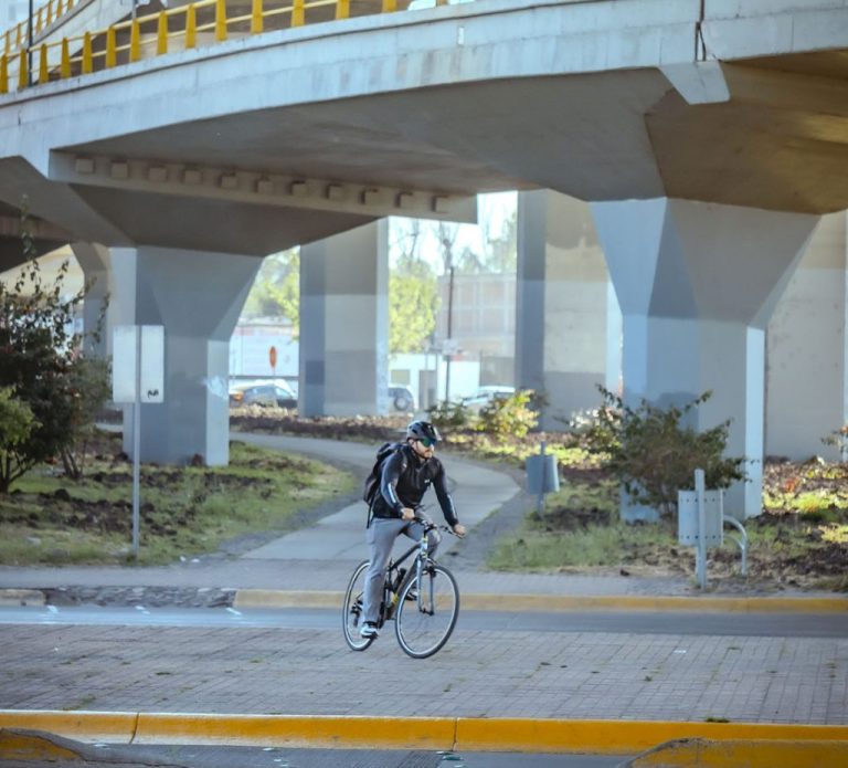 Ciclista urbano rodando bajo un puente vehicular de concreto brutalista en León Guanajuato